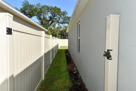 a view of a white house next to a yard and potted plants