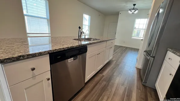 a kitchen with granite countertop a sink a stove wooden floor and cabinets