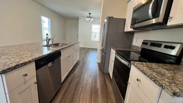 a kitchen with granite countertop stainless steel appliances a sink stove and refrigerator