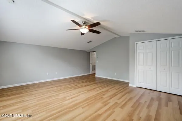 a view of an empty room with a window and wooden floor