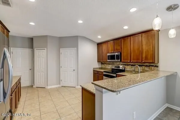 a kitchen with stainless steel appliances granite countertop a stove top oven a sink and a refrigerator