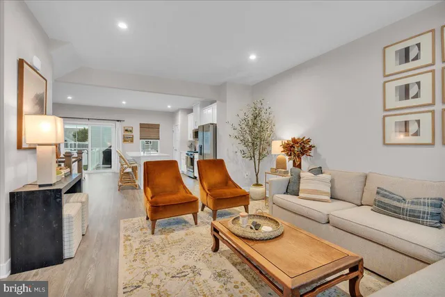 a living room with furniture kitchen view and a wooden floor