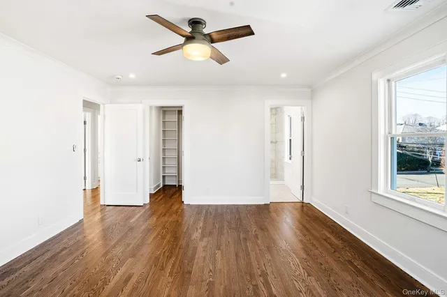 a view of empty room with wooden floor and window
