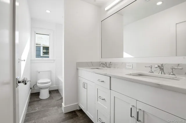 a bathroom with a granite countertop toilet a sink and a mirror