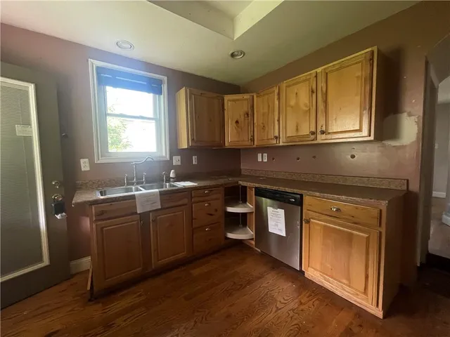 a kitchen with stainless steel appliances granite countertop wooden cabinets a sink and dishwasher with wooden floor