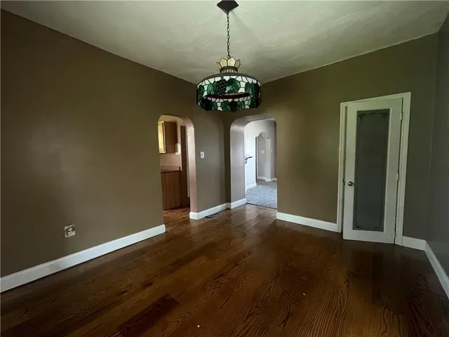 a view of a hallway with wooden floor and chandelier