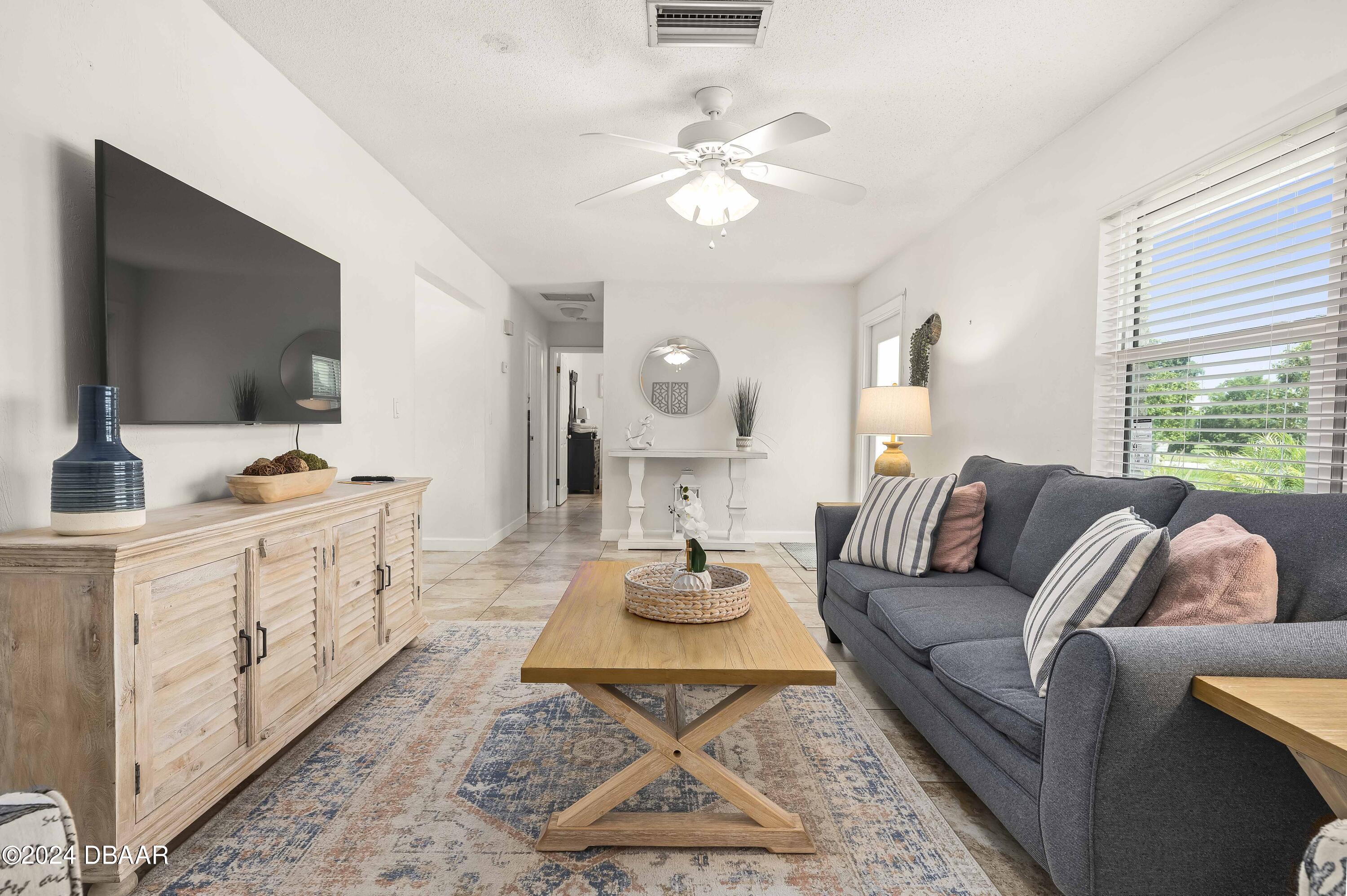 5528 Riverside Drive Port Orange, FL 32127 - Photo 6 of 31 a living room with furniture a flat screen tv and a large window