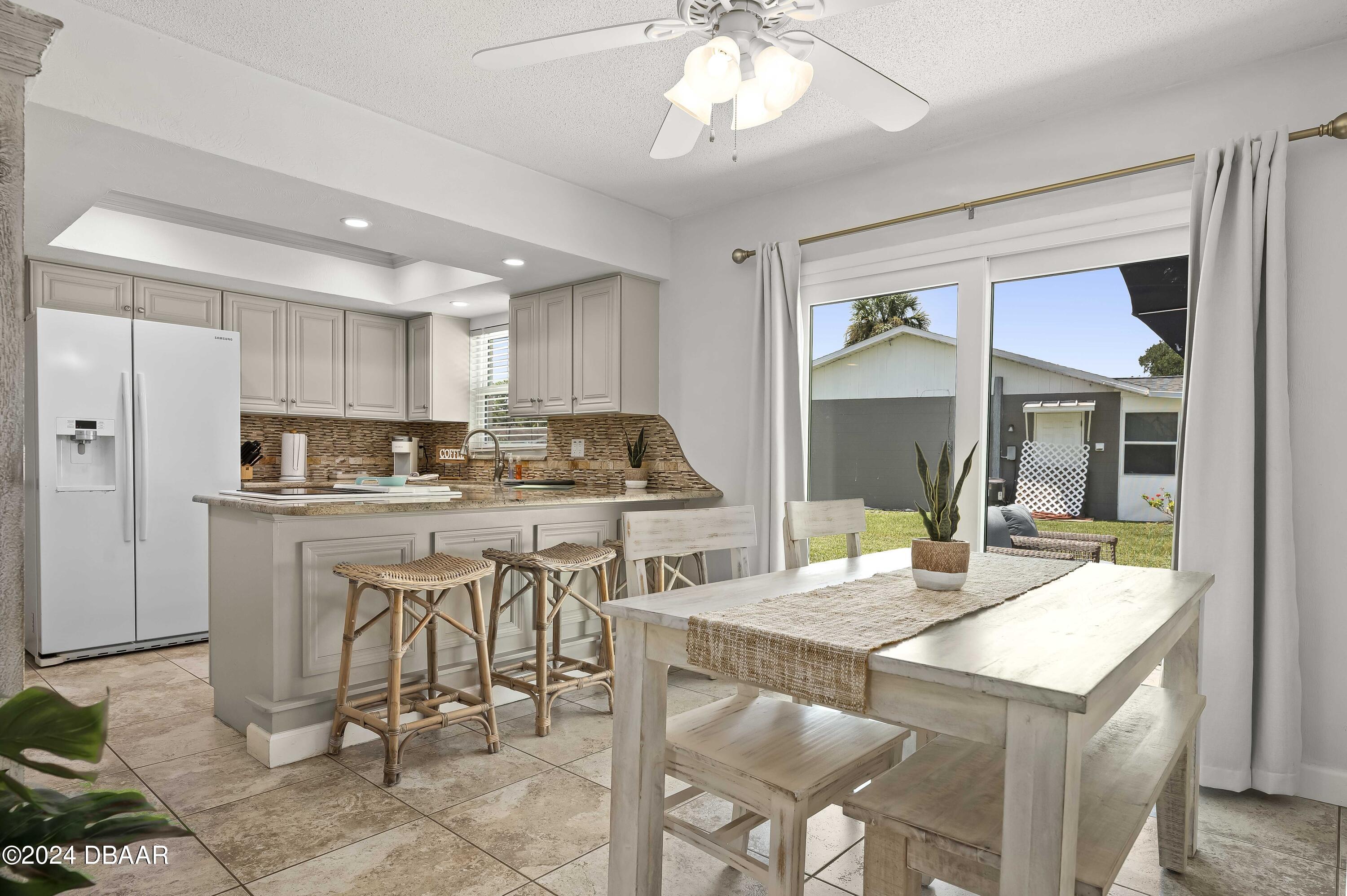 5528 Riverside Drive Port Orange, FL 32127 - Photo 10 of 31 a kitchen with a table chairs refrigerator and cabinets