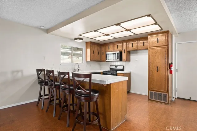 a kitchen with stainless steel appliances kitchen island granite countertop a table chairs sink and cabinets