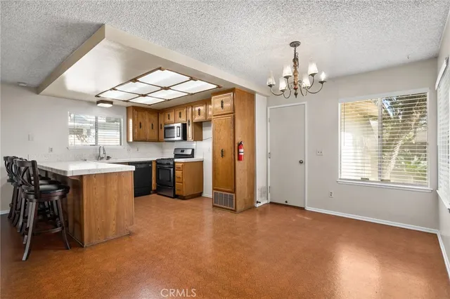 a kitchen with stainless steel appliances granite countertop a sink a stove a refrigerator cabinets and a dining table