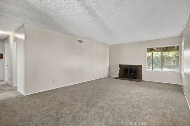 an empty room with a fireplace and a window