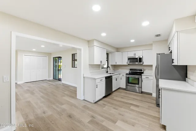 a kitchen with granite countertop a refrigerator and a stove top oven