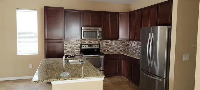 a kitchen with kitchen island granite countertop wooden cabinets a refrigerator and a sink