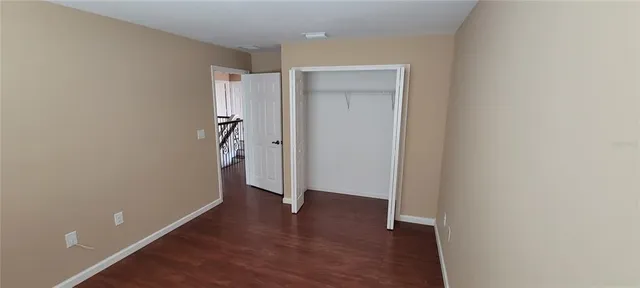 a view of an empty room with wooden floor and a bathroom