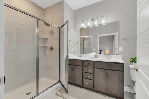 a bathroom with a double vanity sink mirror and shower