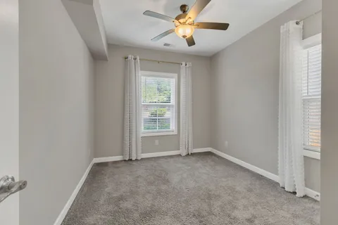 an empty room with windows and fan