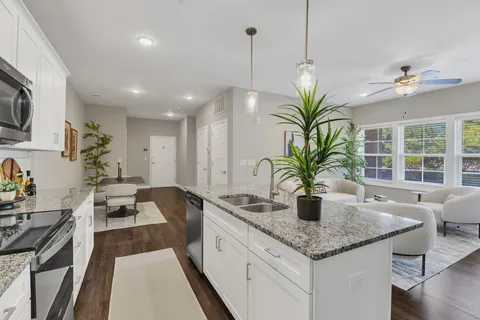 a kitchen with granite countertop a sink a counter top space and living room view