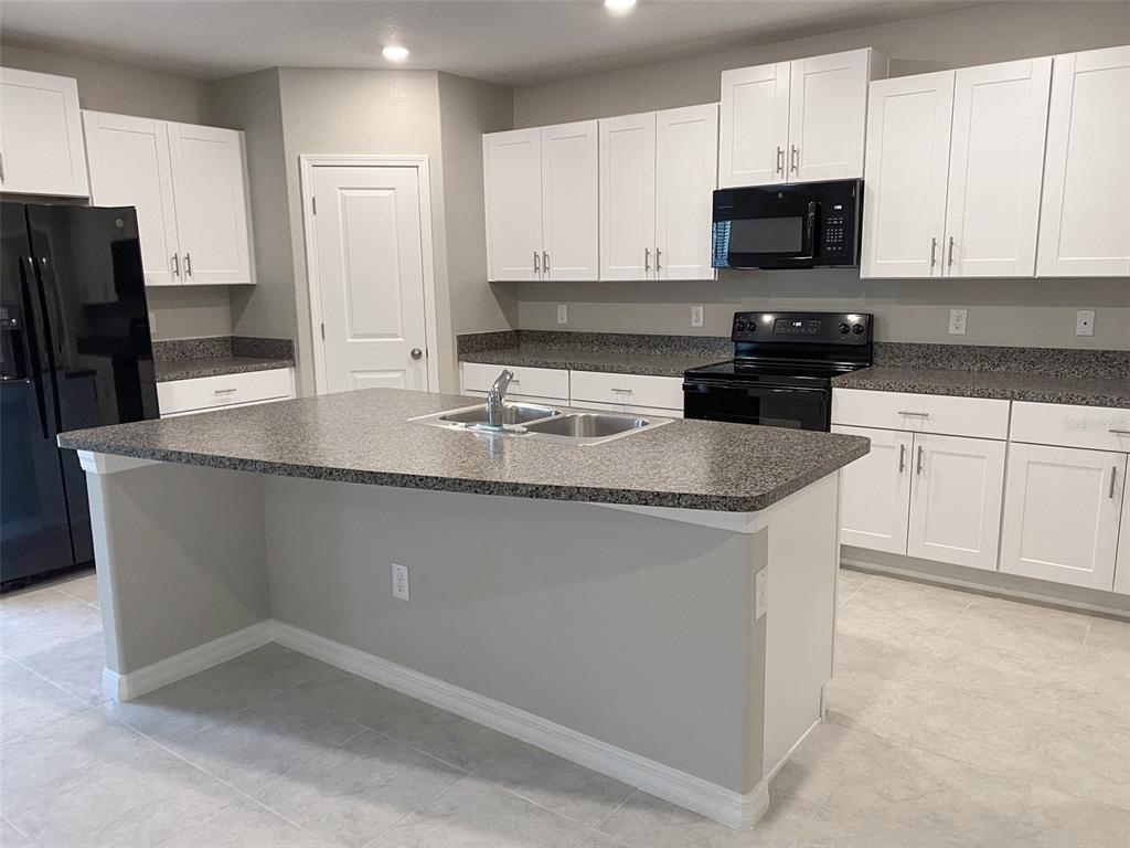 3816 Hanover Drive New Port Richey, FL 34653 - Photo 5 of 64 a kitchen with stainless steel appliances granite countertop a stove a sink a microwave a refrigerator and white cabinets