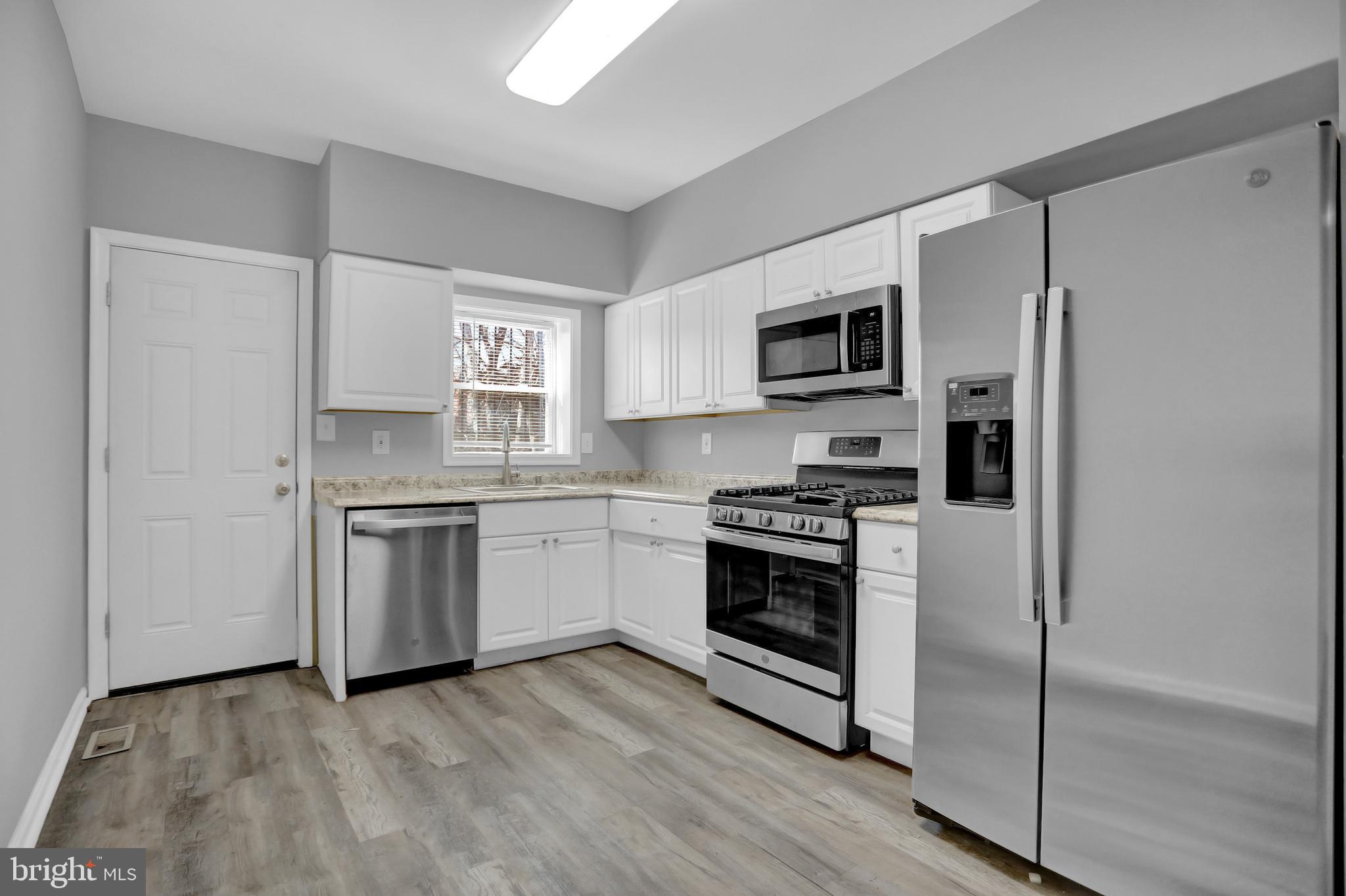 a kitchen with stainless steel appliances granite countertop a stove top oven a sink and a refrigerator