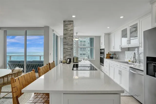 a large kitchen with kitchen island a large window in it and living room view