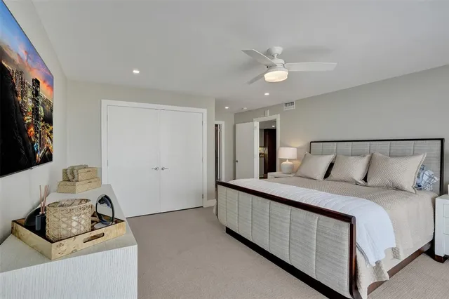 a bedroom with a bed and a flat tv screen on dresser