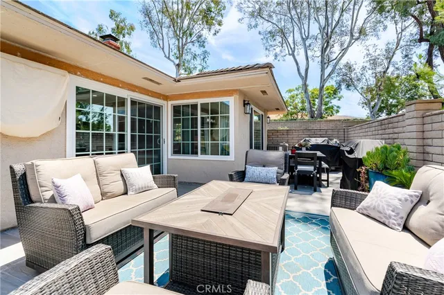 a view of a patio with couches and a table and chairs with wooden floor and fence