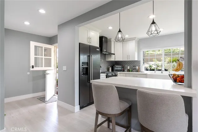 a kitchen with stainless steel appliances granite countertop a dining table chairs refrigerator and sink