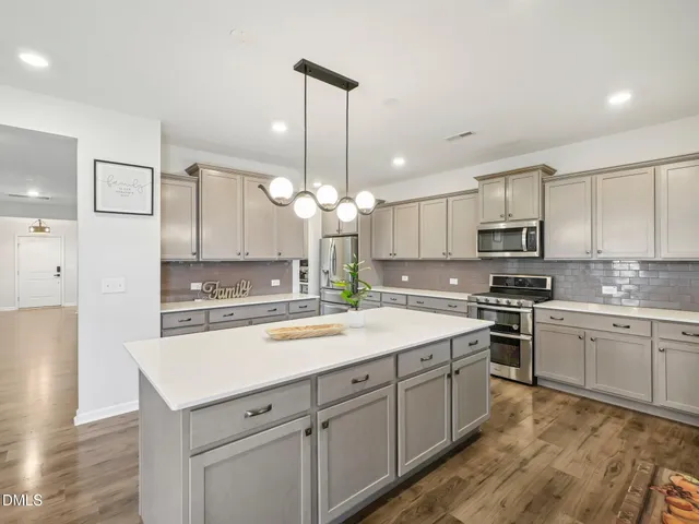 a kitchen with a white center island a sink stainless steel appliances and cabinets