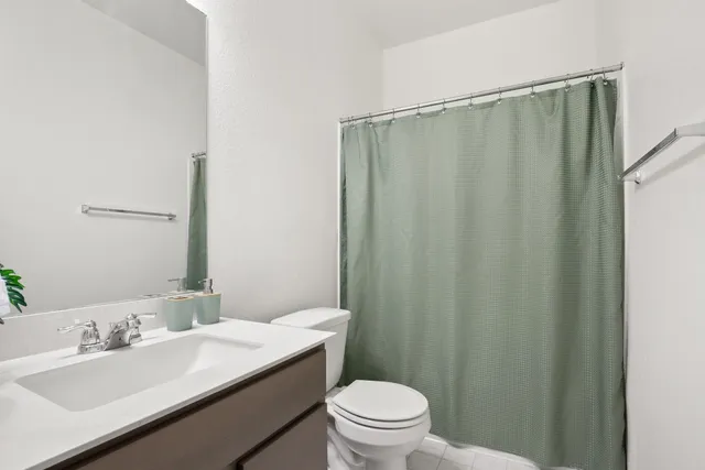 a bathroom with a sink a toilet a mirror and shower curtain