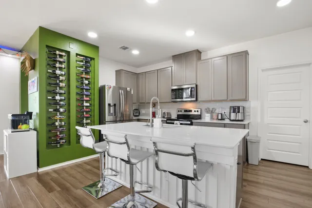 a kitchen with stainless steel appliances granite countertop a refrigerator a stove top oven a sink dishwasher and white cabinets with wooden floor