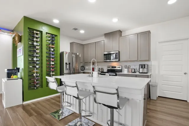 a kitchen with stainless steel appliances granite countertop a refrigerator a stove top oven a sink dishwasher and white cabinets with wooden floor