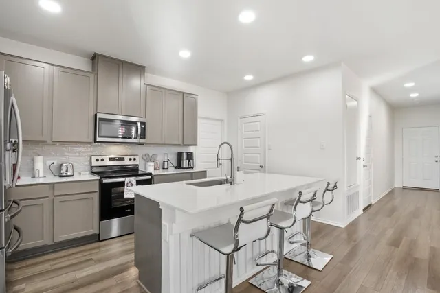 a kitchen with stainless steel appliances granite countertop a stove top oven a sink and white cabinets