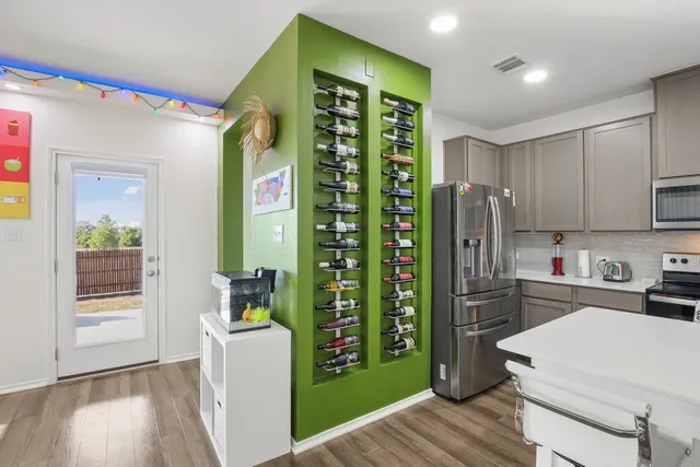 a kitchen with a refrigerator a stove and white cabinets with wooden floor