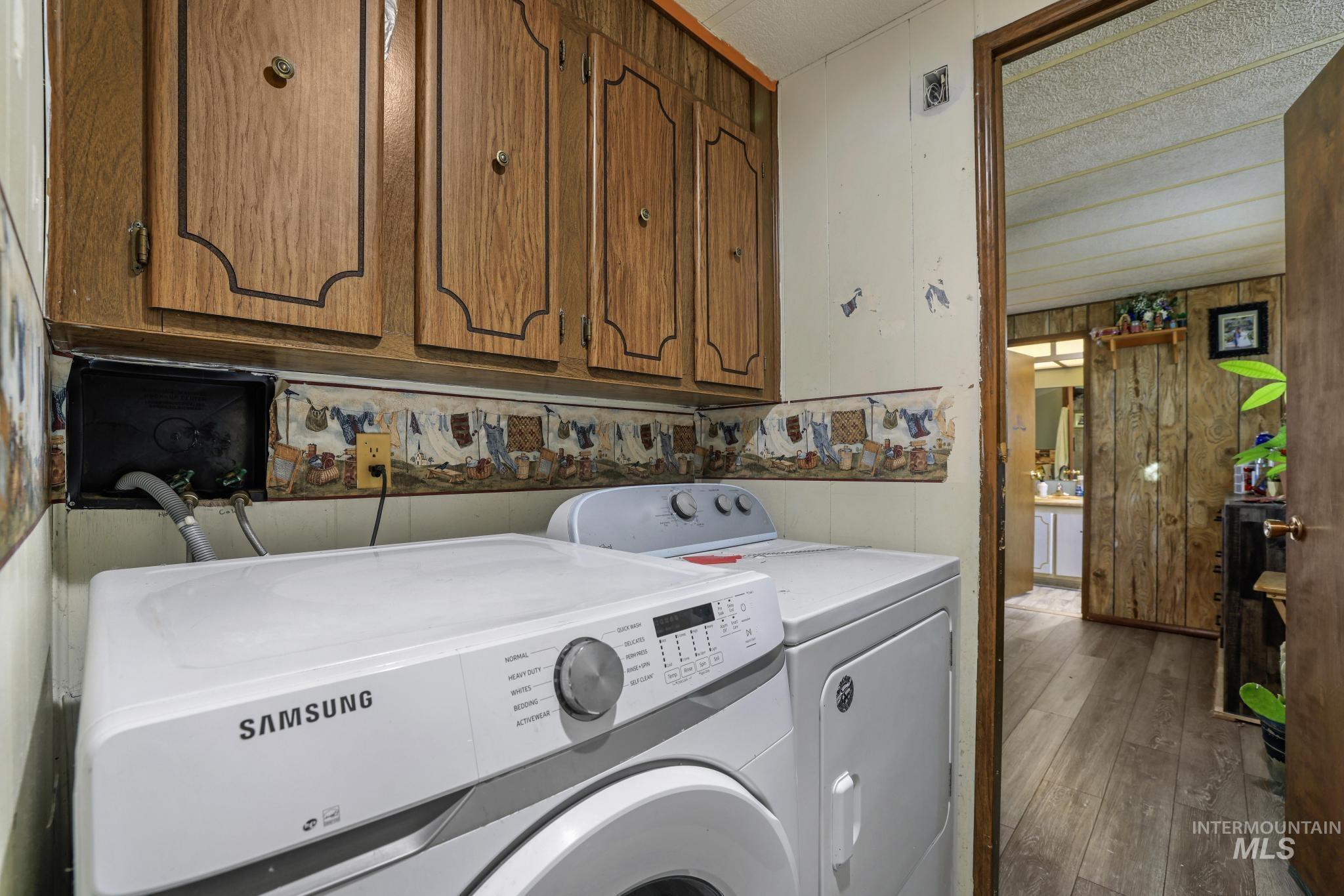 1625 Maple Street, Unit 20 Buhl, ID 83316 - Photo 11 of 17 Washroom featuring wooden walls, cabinet space, hardwood / wood-style flooring, and washer and clothes dryer