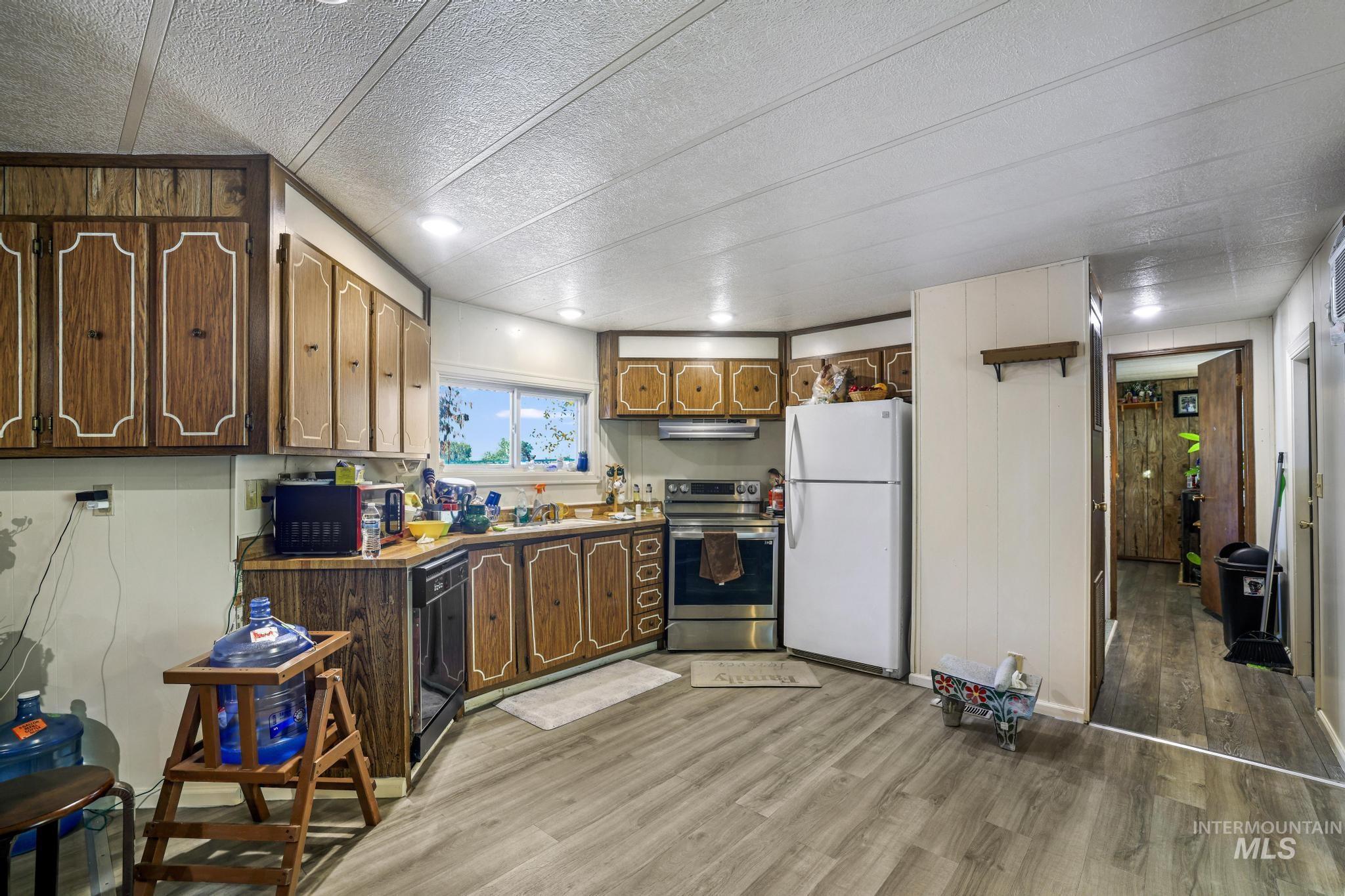 1625 Maple Street, Unit 20 Buhl, ID 83316 - Photo 5 of 17 Kitchen with freestanding refrigerator, stainless steel electric range, light wood-type flooring, a textured ceiling, and black dishwasher