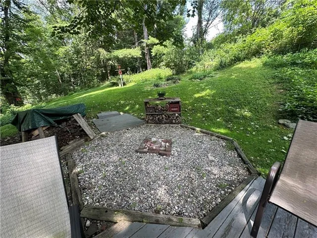 a view of a backyard with table and chairs plants and large trees