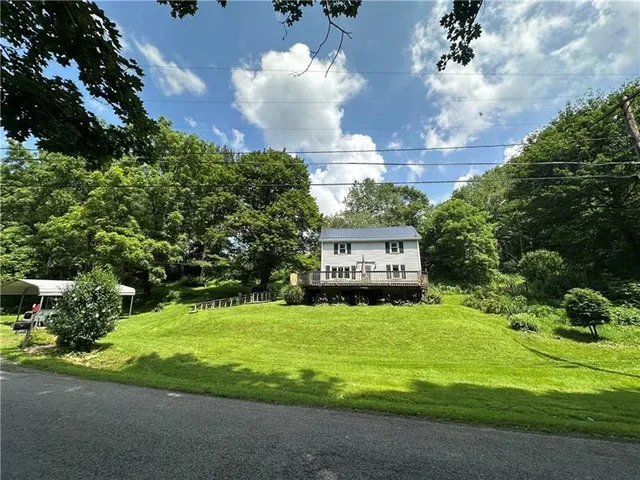 a view of a house with a big yard and large trees