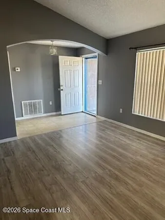 an empty room with wooden floor and windows
