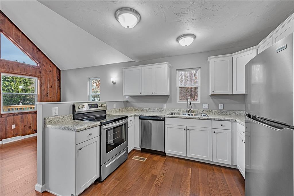 814 Breakneck Road Connellsville, PA 15425 - Photo 9 of 25 a kitchen with stainless steel appliances granite countertop a stove a sink dishwasher a refrigerator and white cabinets with wooden floor