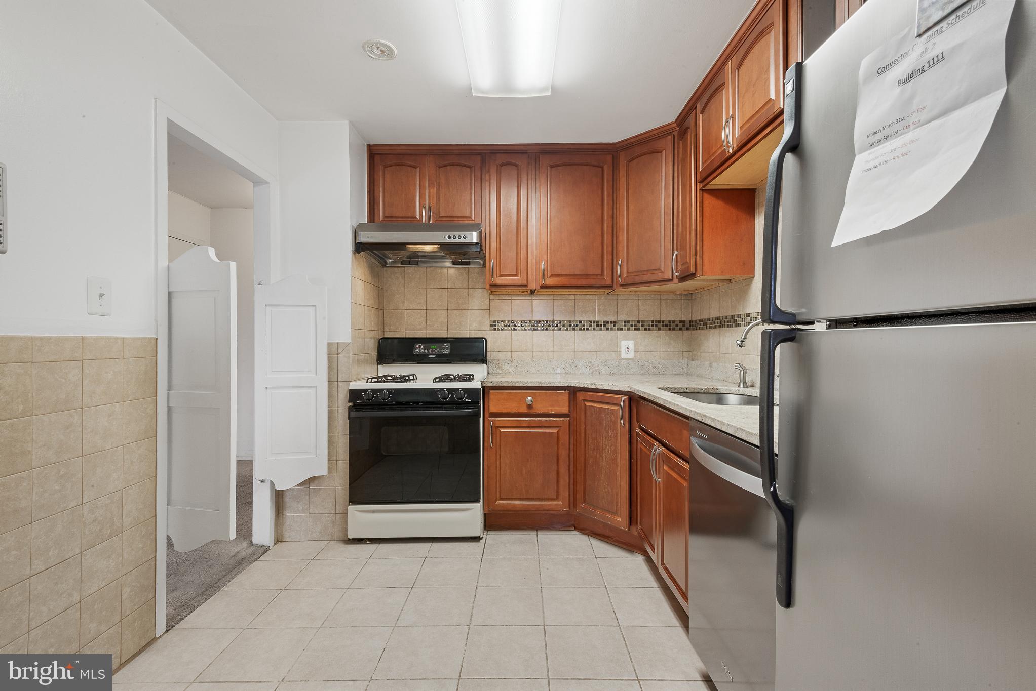 1111 University Boulevard West, Unit 805A Silver Spring, MD 20902 - Photo 17 of 33 a kitchen with stainless steel appliances granite countertop a refrigerator stove top oven and sink