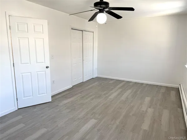 an empty room with wooden floor fan and windows