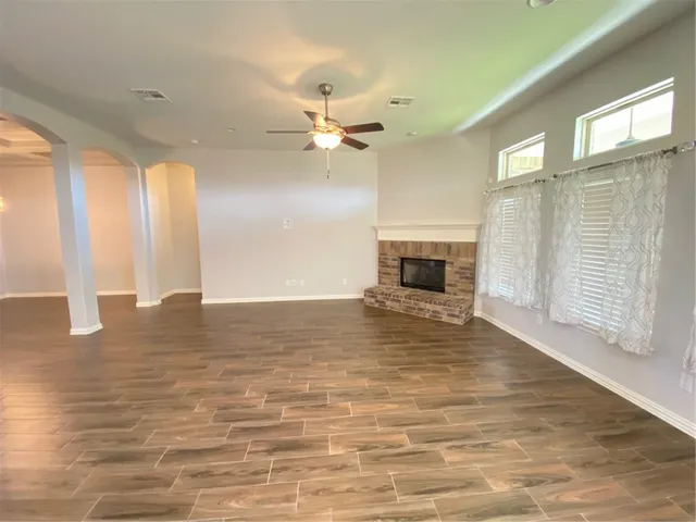 a view of a livingroom with a fireplace a ceiling fan and windows