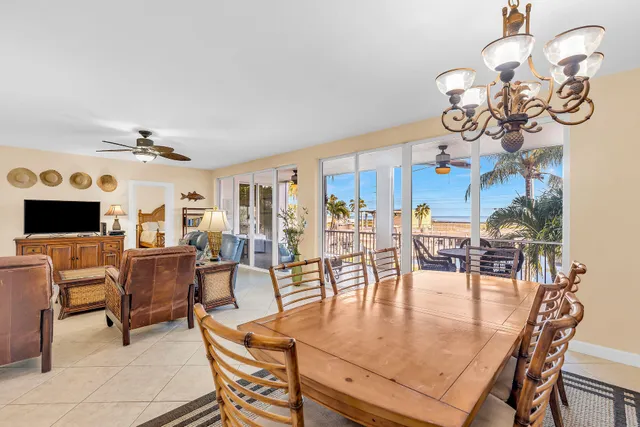 a dining room with wooden floor a chandelier a glass table and chairs