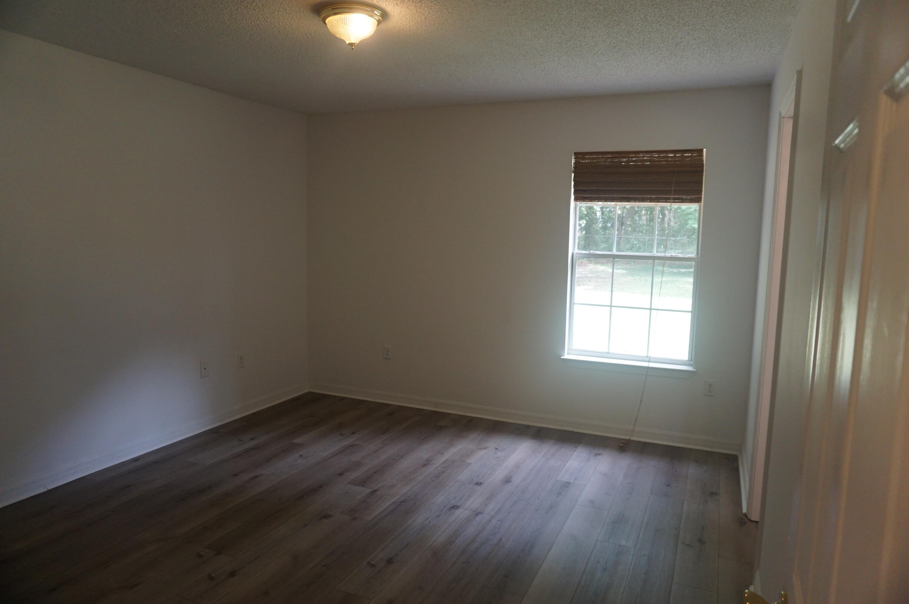 305 Hudson Drive Crestview, FL 32539 - Photo 9 of 16 an empty room with wooden floor and windows