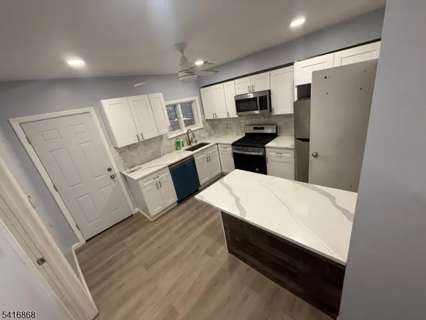 a large white kitchen with sink stainless steel appliances and cabinets