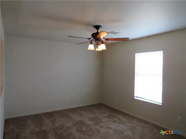 an empty room with windows and chandelier fan