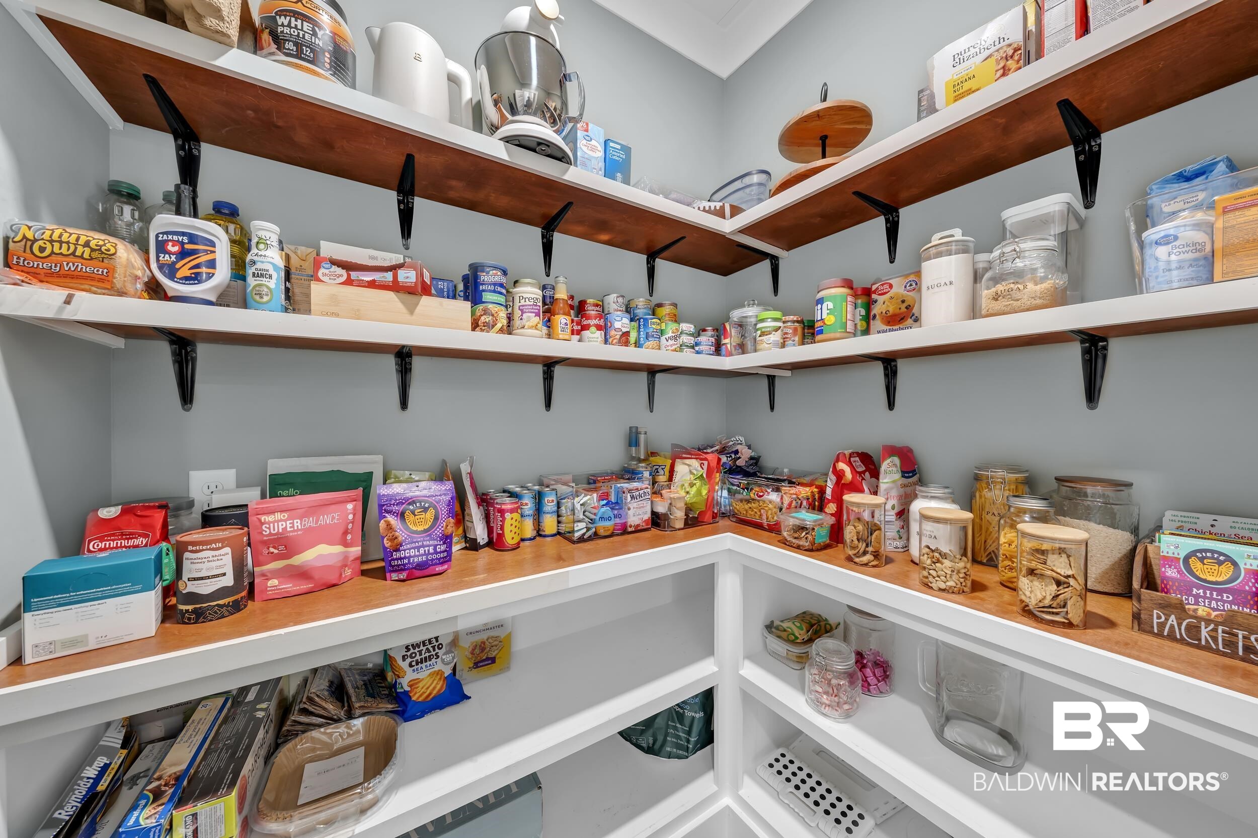 6576 Ranch Loop Road East Grand Bay, AL 36541 - Photo 17 of 39 Functional corner pantry featuring extensive built-in shelving, durable wood-finish surfaces, and white lower cabinetry