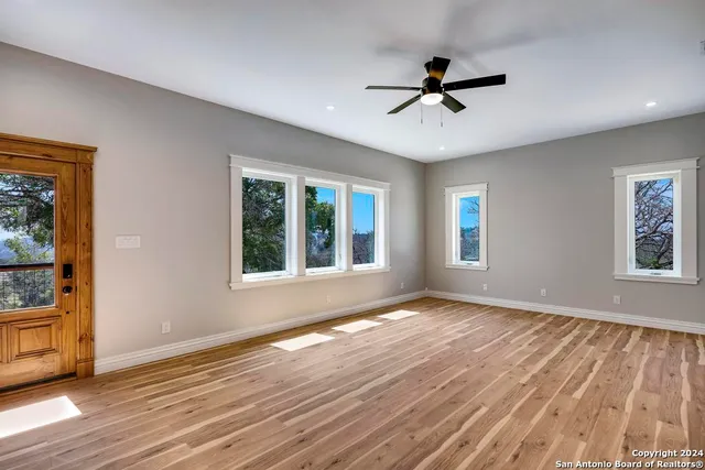 a view of an empty room with a window and wooden floor