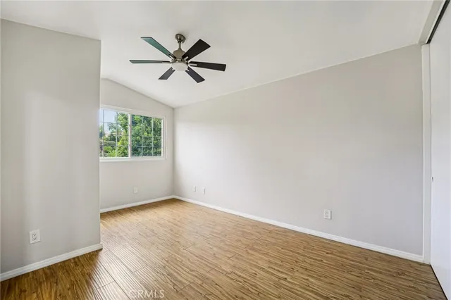 a view of empty room with wooden floor and fan
