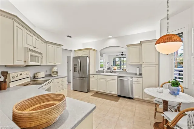 a kitchen with stainless steel appliances granite countertop a sink a stove a refrigerator cabinets and chairs